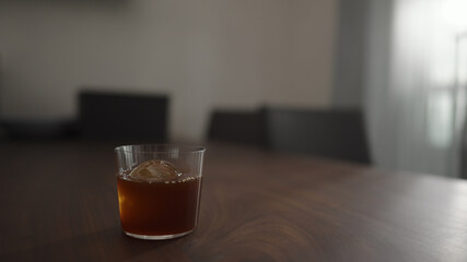 cold brew coffee over ice ball in tumbler glass on walnut table