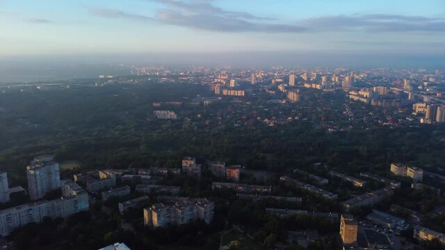 Aerial left to right panoramic view on city in sunrise light with clouds and sun shine. Early morning flight above sleeping city. Kharkiv, Ukraine city center park and residential district