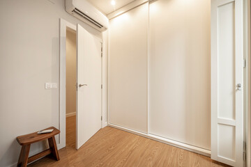 White fitted wardrobe with sliding doors with air conditioning in a bedroom of a vacation rental apartment