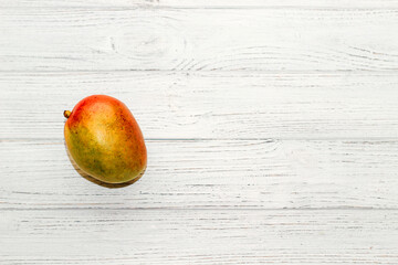 ripe juicy mango lies on a wooden white table.
