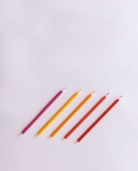 composition of colored pencils with red and yellow tones lined up on a white background