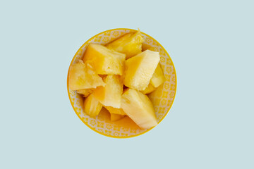 Top view image of ripe pineapple chunks inside a yellow bowl
