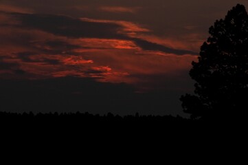 The clouds glow a vibrant red and orange as the sun prepares to crest over the distant horizon.