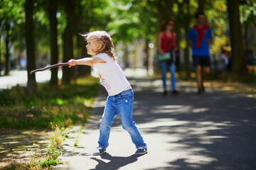 Obraz premium Adorable preschooler girl playing with a stick
