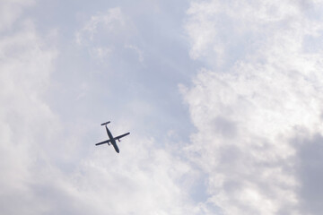 Blue sky with white clouds and a flying plane. View from the top