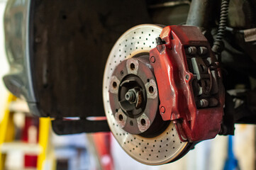 Red brake caliper of performance car. - obrazy, fototapety, plakaty