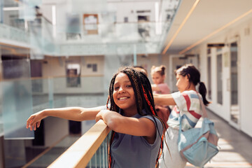 Portrait of smiling African-American girl enjoying first day at school and looking at camera while standing in sunlight, copy space