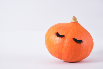 pumpkin with false eyelashes on gray background