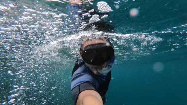 Man in snorkel mask snorkeling underwater in slow motion. Vacation, freediving and travel concept.