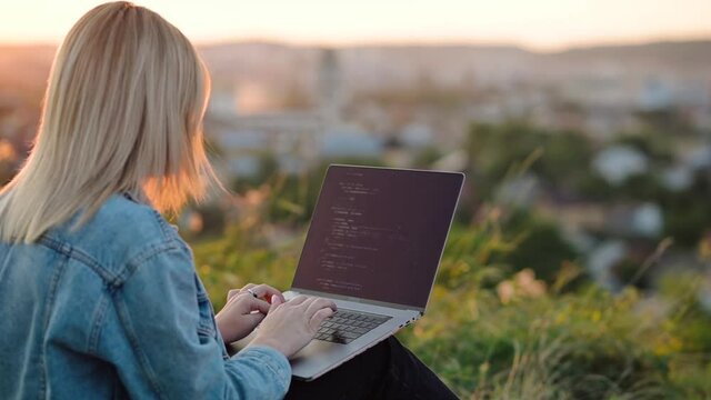 View through a young woman, freelance data source, working in nature with city and sunset views, coding big data programming, artificial intelligence engineering, IT engineering working on an