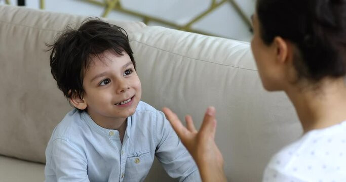 Cute mixed race preschool boy do exercises for correct sound pronunciation, repeat words gesturing, practising speech with therapist or mother at home. Voice ability problem, speaking lesson concept