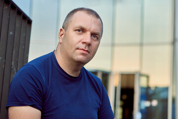 Caucasian middle aged man sits near office building.