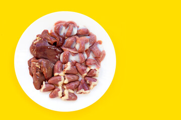 Mixed chicken entrails in white plate on yellow background.