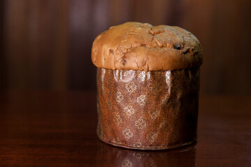 Panettone on the wooden table with textured brown woody background. Panettone concept. Space for text. Christmas concept.

