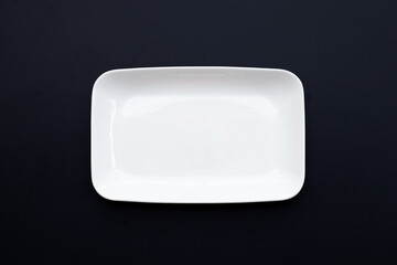 Empty white dish plate on dark wooden background.