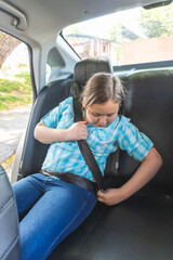 Blonde girl adjusting her seat belt in the car