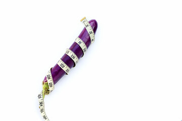 Long purple eggplant wrapped in measuring tape on white background.