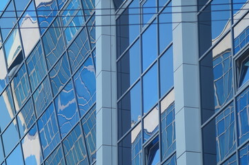 Obraz premium Photo of an urban texture. Part of the facade of a new office building. Commercial real estate. Glass, concrete, plastic, reflections, distortions, building materials.
