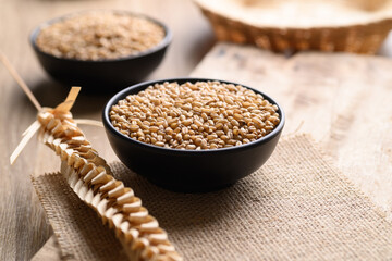 Wheat grain in a black bowl on wooden background