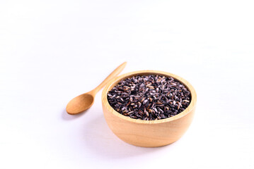 Purple glutinous rice grain in a wooden bowl with spoon on white background, Thai rice