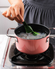Put Pandan Leaf on a Pink Pan Contain Sugar Palm Fruit (Kolang Kaling). Cooking Process Making Manisan Cangkaleng for Ramadhan Breakfasting Takjil