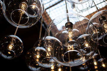 A view of a background of modern glass globe hanging light fixtures, seen in an interior facility. - Powered by Adobe