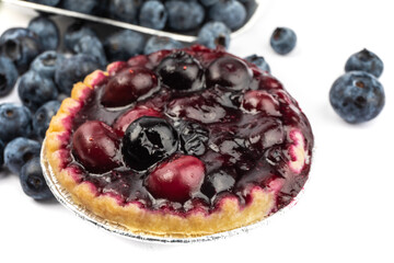 home made blueberry tarts and a baker's scoop of fresh ripe blueberries isolated on white