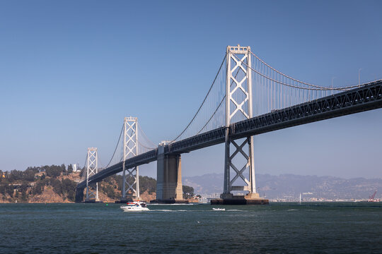 Landscape of San Francisco - Oakland bay bridge with running boat.