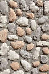 Stone decorative wall texture background. Concrete wall embedded with pastel colored stones. 