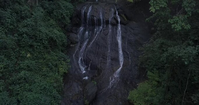 Refreshing View Of Water Splashing Over Rocky Hills With Growing Leafy Plants At Cotigao Wildlife Sanctuary Netravali, South Goa, India. - Pullback Shot 