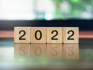 2022, new year concept, numbers on wooden cube blocks on brown wood desk and green nature...