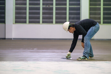 Construction workers are using trowel spreading moisture blocking epoxy primer for Self-leveling...