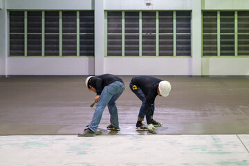 Construction workers are using trowel spreading moisture blocking epoxy primer for Self-leveling...