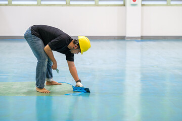 Construction worker using trowel spreading epoxy putty for Self-leveling method of epoxy floor finishing work