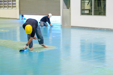 Construction workers are using trowel spreading epoxy putty for Self-leveling method of epoxy floor...