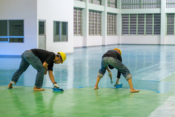 Construction workers are using trowel spreading epoxy putty for Self-leveling method of epoxy floor finishing work