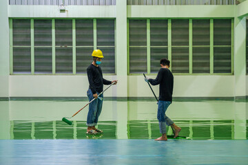 Construction workers are using rollor spreading green epoxy coating floor for Self-leveling method...