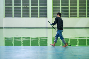 Fototapeta na wymiar Construction workers are using rollor spreading green epoxy coating floor for Self-leveling method of epoxy floor finishing work