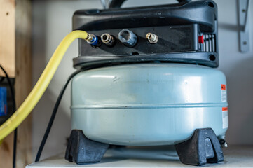 Selective focus on a hose connected to a Pancake air compressor sitting on a shelf