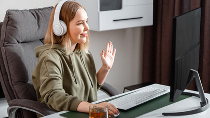 Teenager girl talking on video communication during remote online education using pc computer and headphones at home.Casual woman waving her hand while talking via video call. Long web banner