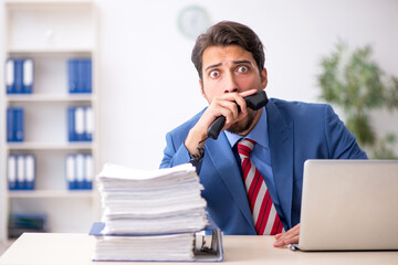 Fototapeta premium Young male employee unhappy with excessive work in the office