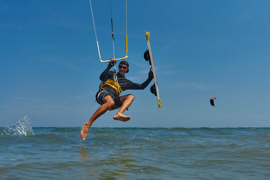 Kite surfer jumps with kiteboard in transition