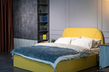 a spacious bedroom in dark colors with a bright yellow bed