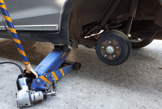 A car on jack with wheel removed showing brake discs