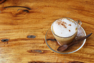 A cup of cappuccino coffee on a wooden table