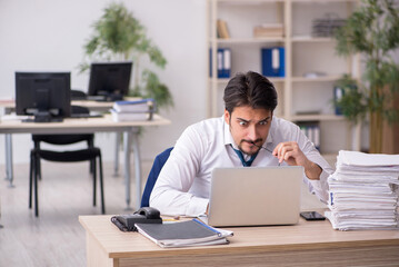 Naklejka premium Young male employee unhappy with excessive work in the office