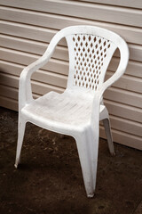 A white plastic chair stands near the backyard house.