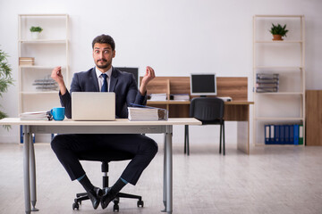 Young male employee doing yoga exercises during break