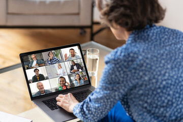 Aged business woman using laptop for having virtual team meeting on video call with different people, work from home office or coworking, online meeting, briefing, brainstorming