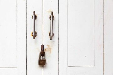 The padlock hangs on the white wood door